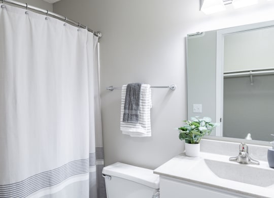 a bathroom with a white sink and toilet and a white shower curtain
