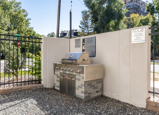 a barbecue grill in the corner of a wall next to a fence
