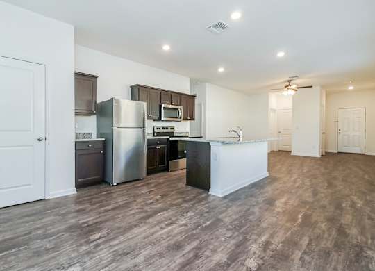 A kitchen with a refrigerator, microwave, and oven.