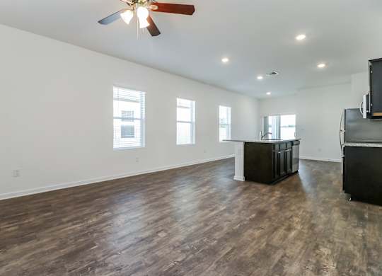 A room with a ceiling fan and wooden flooring.