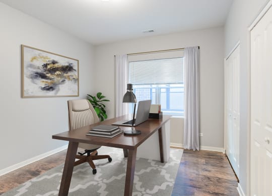 a home office with a large window and a desk with a laptop