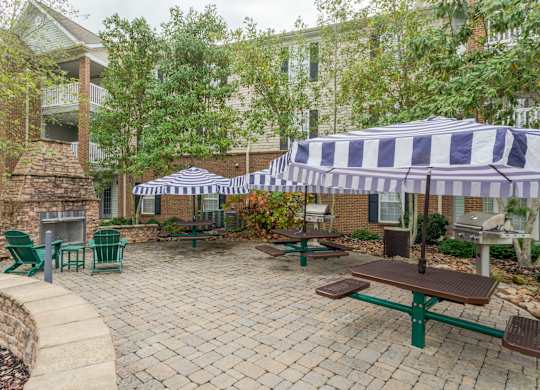Apartments in Sevierville for Rent – Overlook at Allensville -   A patio with a table and chairs under a striped umbrella.
