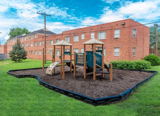 a playground in a yard in front of a brick building