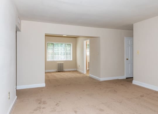 the spacious living room and dining room of an empty house