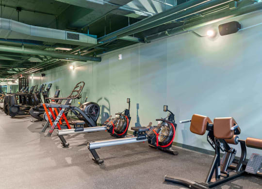a gym with bikes and weights in a room with a white wall