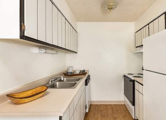 Classic kitchen with white cabinetry and essential appliances at Trailgrove Apartments in Southeast Denver.