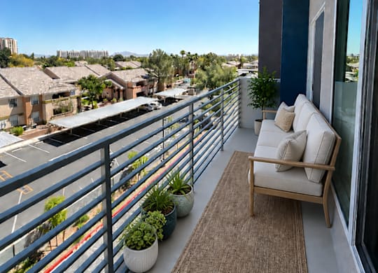 A balcony with a couch and a chair overlooking a street.