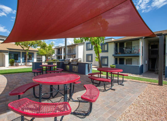 a covered patio with red tables and chairs