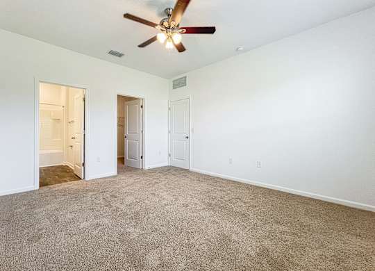 A room with a ceiling fan and carpeted floor.