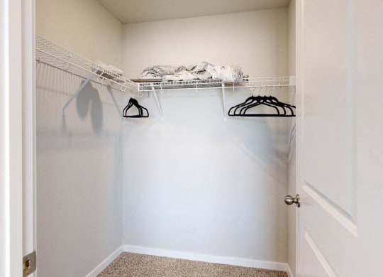 a closet with white walls and shelves and a white door