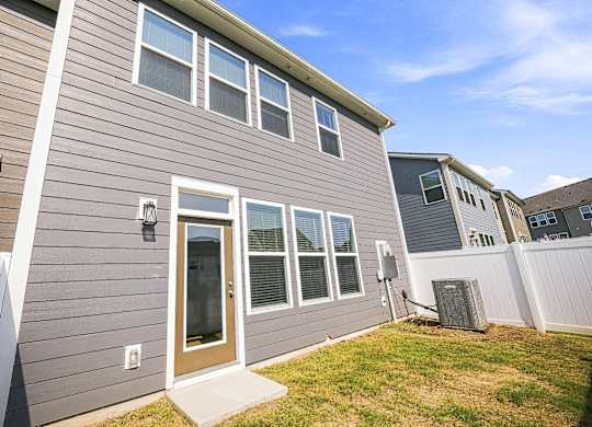A grey house with a brown door and a small window.