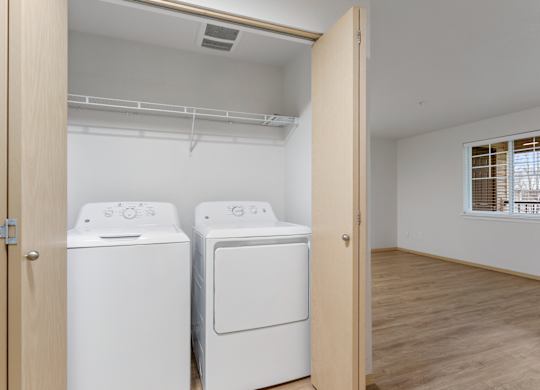 Apartments for Rent in Vancouver, WA - Reflections at the Park - Laundry Closet with Washer and Dryer, Wood-Style Flooring, and Wire Rack Shelf.