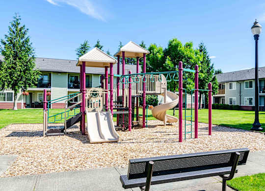 Vancouver, WA, Pet-Friendly Apartments - Reflections at the Park - Children's Playground with Slides, Bench, and Surrounding Lawn