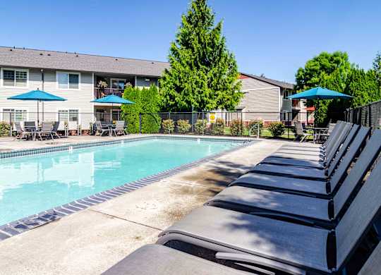Apartments in Vancouver, WA - Reflections at the Park - Pool with Lounge Chairs, Umbrella Tables, and Chairs.