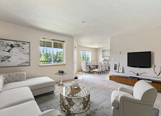 One Bedroom Apartments in Vancouver, WA - Reflections at the Park - Living Room with Carpeting, Sectional Couch, TV, and View of Dining Area.