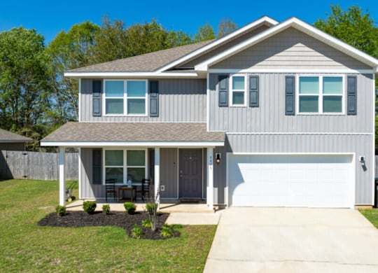 a gray house with a white garage door and a lawn