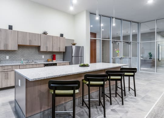 a kitchen with a large island with bar stools and a stainless steel refrigerator