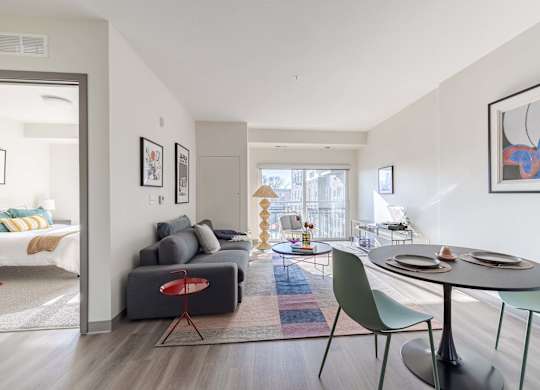 A modern living room with a grey couch, a red chair, a green chair, and a round table.