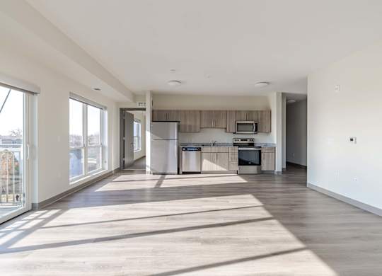 A spacious living room with a kitchen in the background.