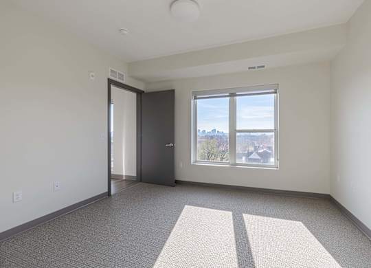 A room with a door, window, and carpeted floor.