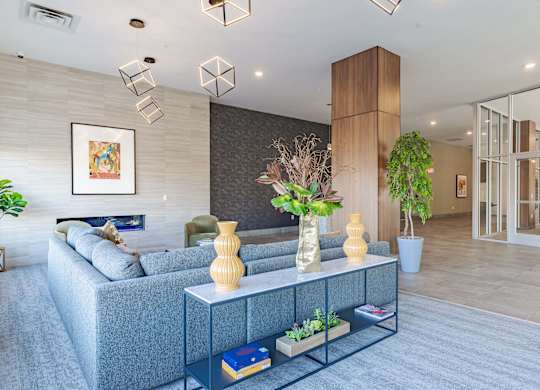 A modern living room with a grey sofa, a white coffee table, and a large painting on the wall.