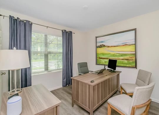 A room with a desk, chair, and a painting on the wall.