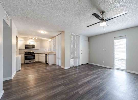 A spacious living room with a kitchen in the background.