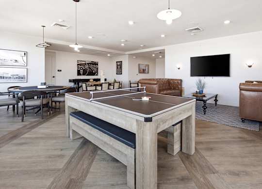 A ping pong table is in the middle of a room with a couch and a TV.