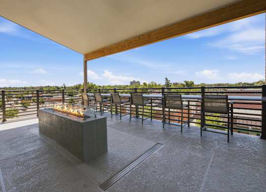A patio with a fire pit and chairs overlooking a body of water.