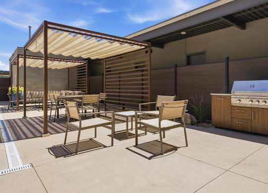 A patio with a table and chairs and a grill.