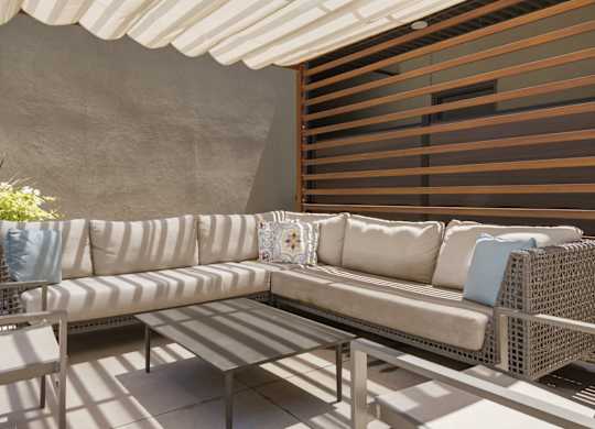A white couch with blue pillows is on a patio.