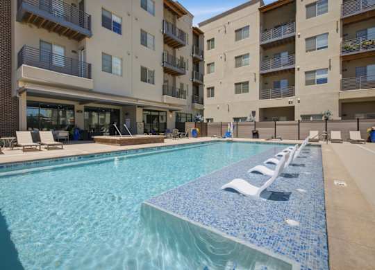 A large swimming pool in front of apartment buildings.