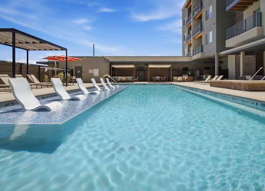 A long rectangular pool with white sun loungers on either side.