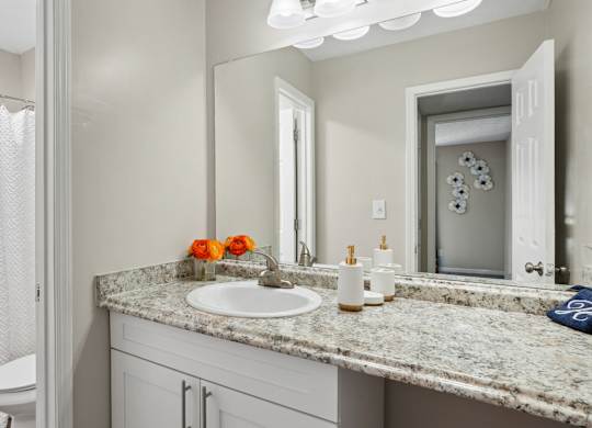 A bathroom with a granite countertop and a white shower curtain.