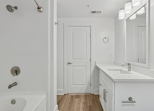 A white bathroom with a tub, sink, and mirror.