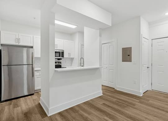 A kitchen with white cabinets and a stainless steel refrigerator.