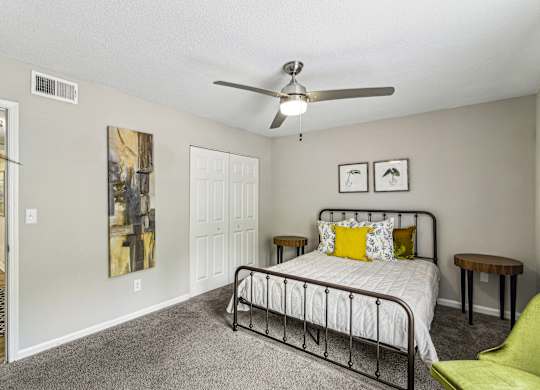 A bedroom with a bed, a chair, and a painting on the wall.
