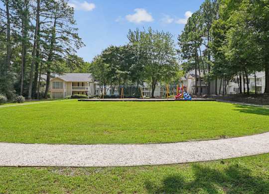 A park with a playground and a house in the background.