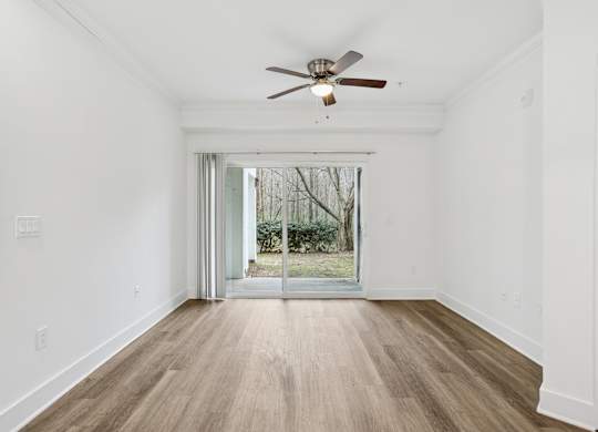A room with a ceiling fan and sliding glass doors leading to a garden.