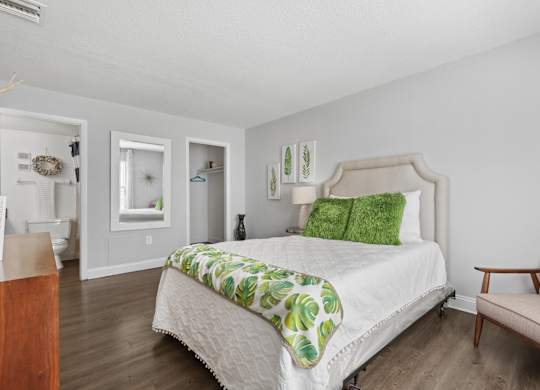 A bedroom with a bed, chair, and a mirror.