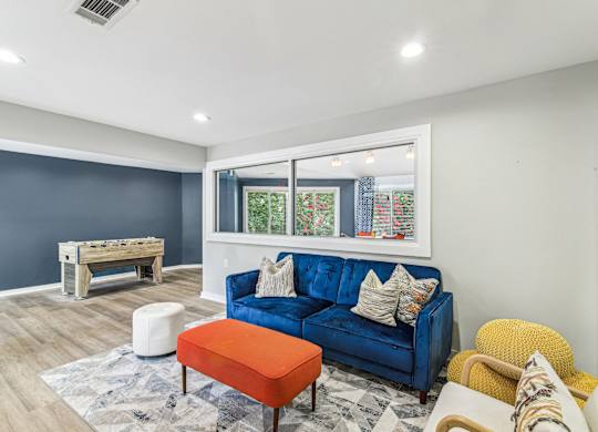 A blue couch with a white pillow is in the middle of a room with a window.