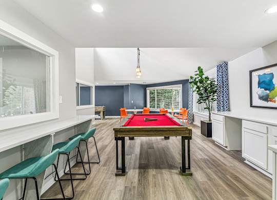 A room with a pool table and chairs.