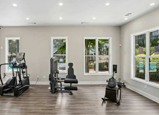 A spacious room with a treadmill, stationary bike, and rowing machine.