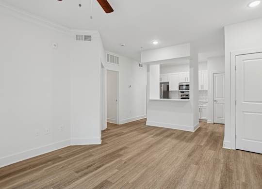 A spacious room with wooden flooring and white walls.