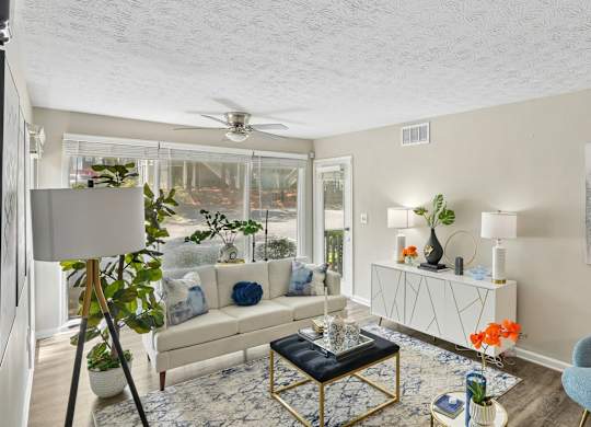 A living room with a white couch, a blue chair, and a painting on the wall.