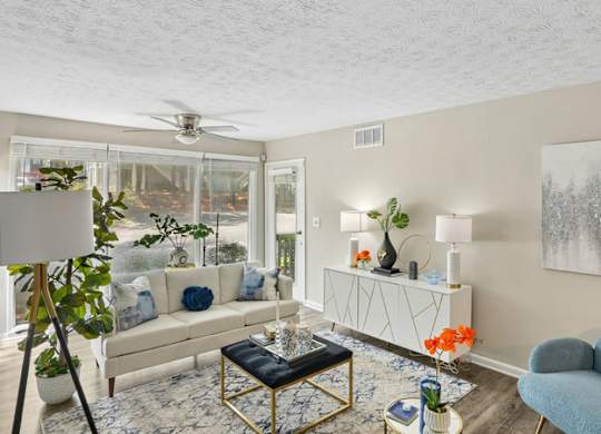 A living room with a white couch, a blue chair, and a painting on the wall.