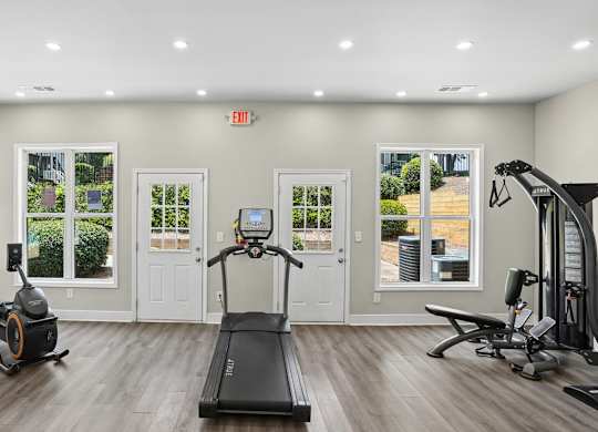 A spacious gym with a treadmill, elliptical machines, and other exercise equipment.