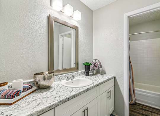 A bathroom with a marble countertop and a large mirror.