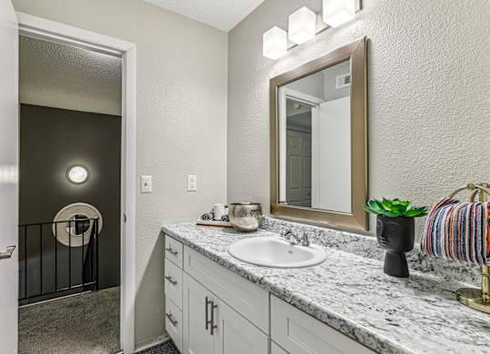 A bathroom with a sink, mirror, and a striped towel.