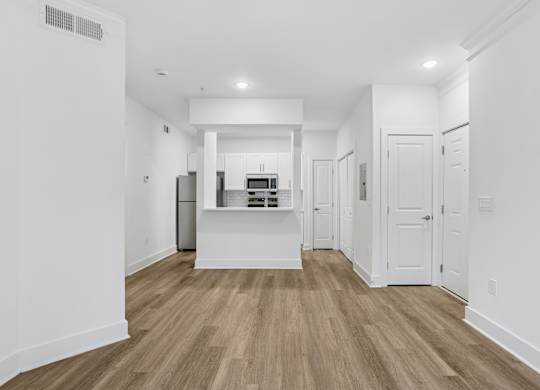 A kitchen with white cabinets and a wooden floor.